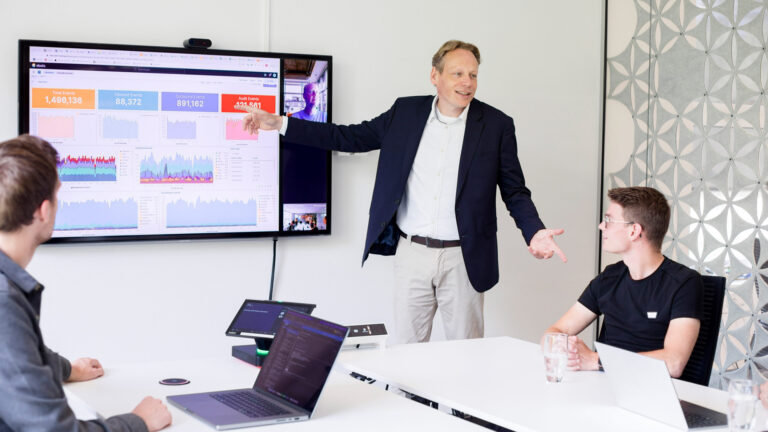 Drie Intermax collega's in vergadering waarbij een collega presenteert voor een digitaal beeldscherm
